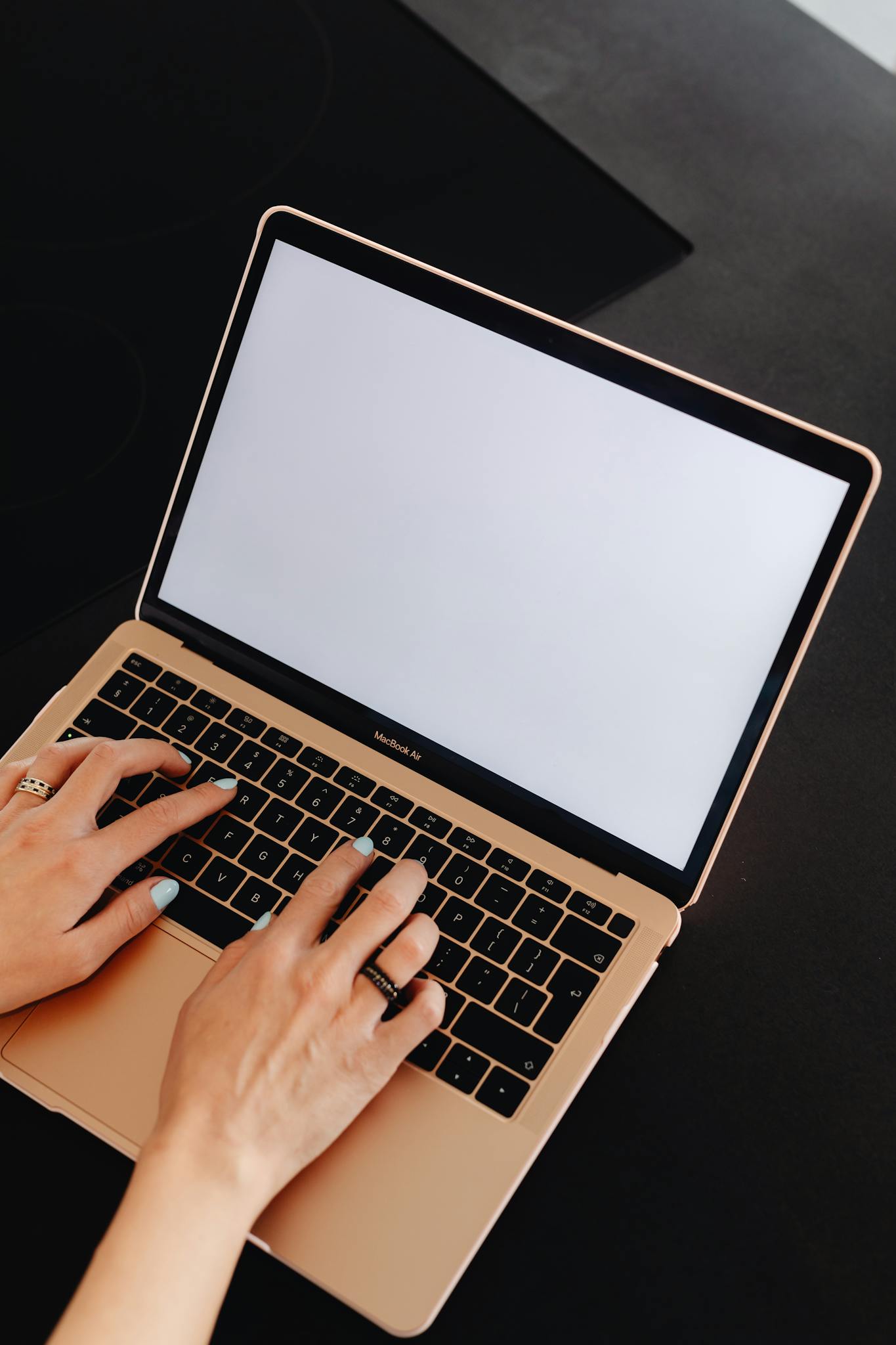 Close-up of hands typing on a MacBook with an empty screen and space for copy.